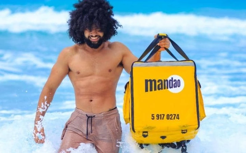 Hombre joven cubano con mochila de mAndao delivery service en la playa de Varadero, matanzas, Cuba.