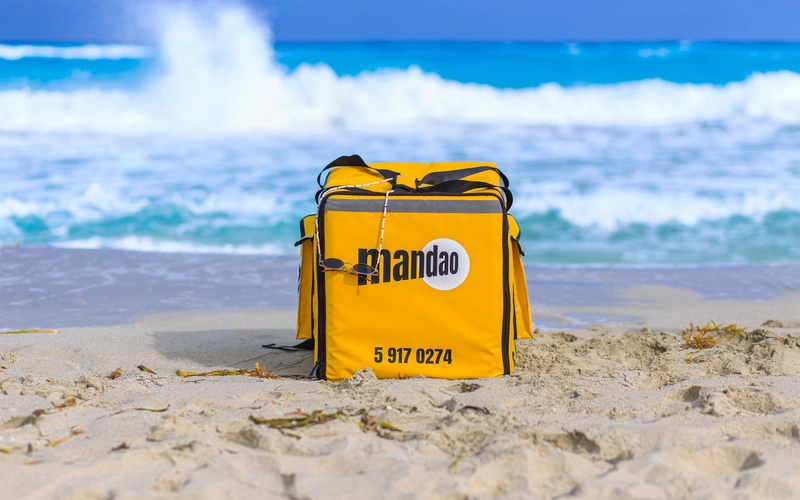 Backpack of the delivery service Mandao in the sand of Varadero beach, with view of the sea in Matanzas, Cuba