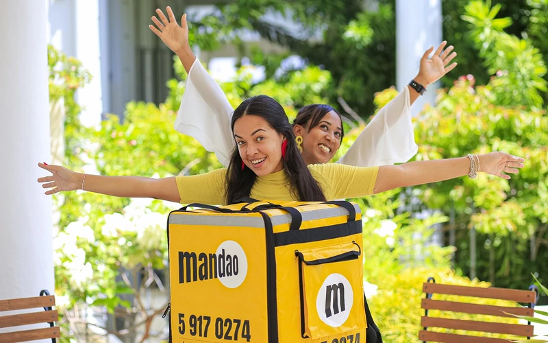 mujeres jÃ³venes cubanas sonreindo jugando con mochilas del servicio de delivery mandao en La Habana, Cuba